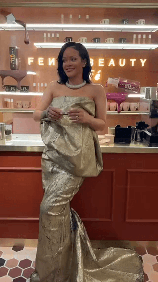 Fenty Beauty: Rihanna in a gold gown holding a lipstick in a Fenty café