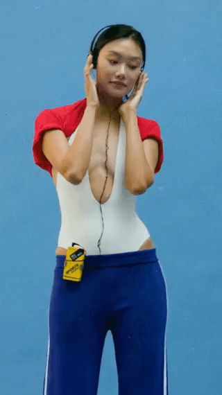 Anthropologie: a model in a white bodysuit, red sleeves and headphones