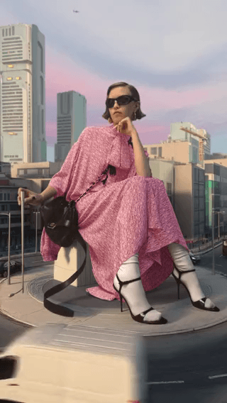 Balenciaga: a model in a pink dress perched above a city street