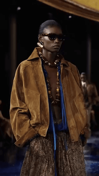 Saint Laurent: a model in a tan suede jacket on a runway