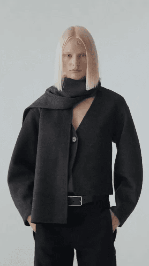 A model wearing a black wool coat and scarf